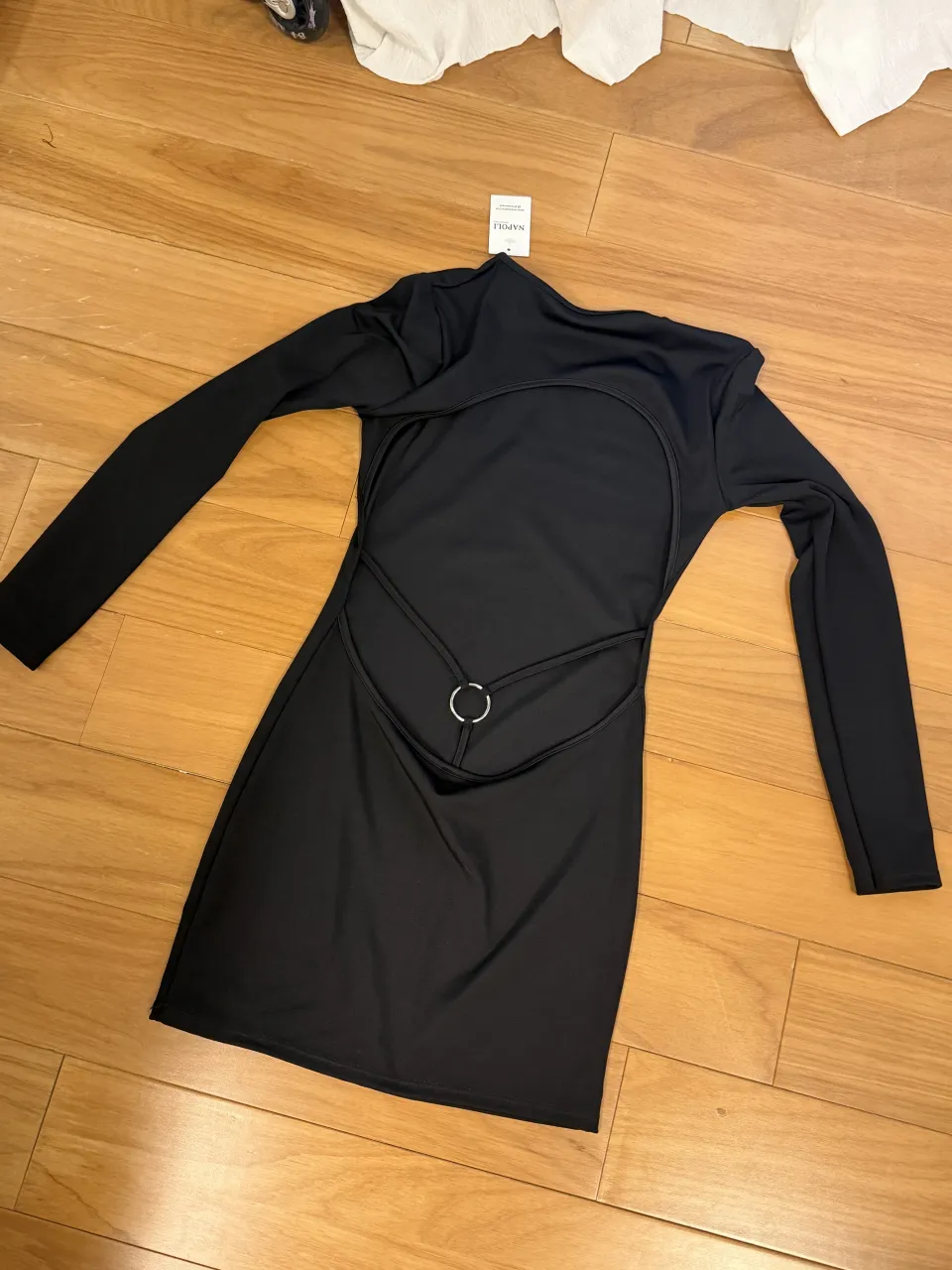 Vestido negro de manga larga con detalles de tiras y un aro metálico en la espalda.