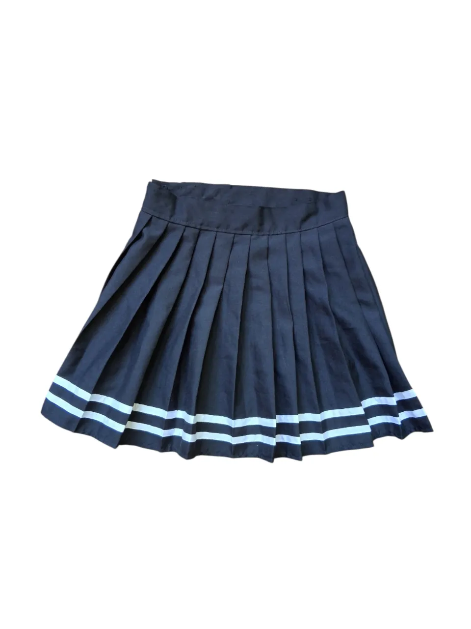 Pollera negra plisada con detalles de franjas blancas en la parte inferior. Ideal para un look casual o deportivo. Talle unico. Es tipo wrap, abierta mide 104 cm y se ajusta al ancho de cintura con botones. De largo mide 43 cm.