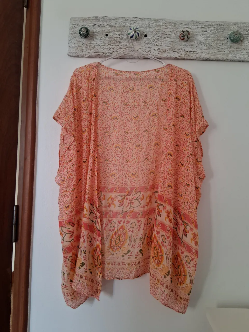 Kimono estampado en tonos rosas, naranjas y amarillos. Posee un diseño floral y de estilo paisley en la parte inferior. Talle único. La tela es fresca y muy liviana.