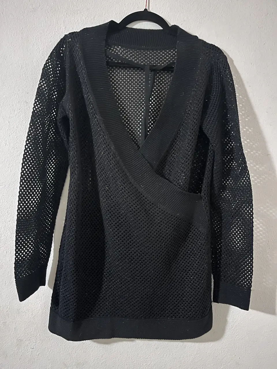 Sweater negro de red con brillos, cuello en V y diseño cruzado. Ideal para un look moderno y sofisticado. Talle S.