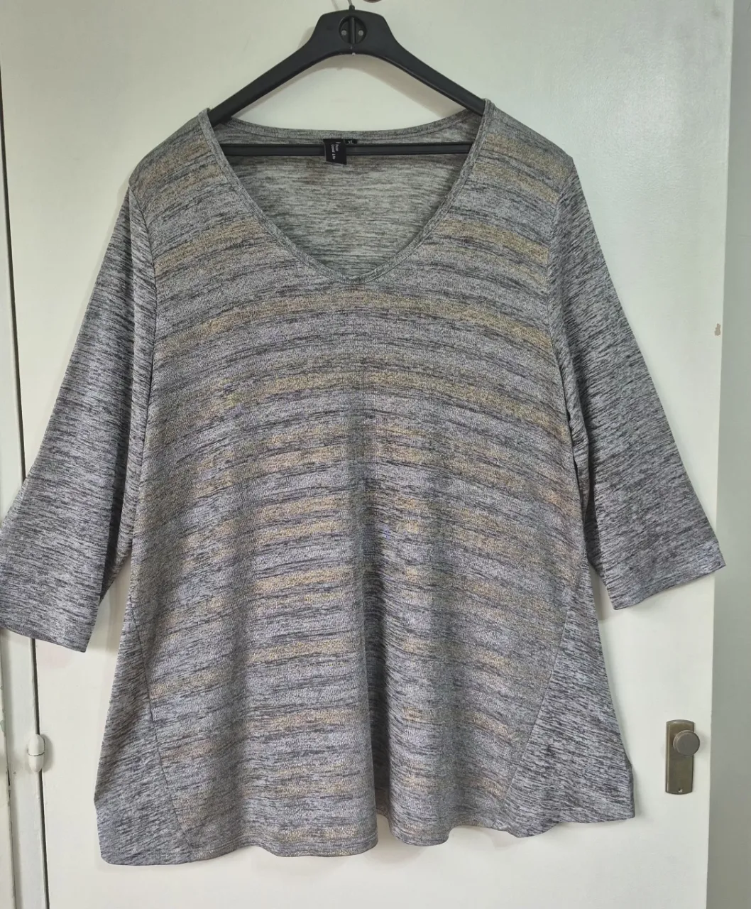 Remera manga 3/4 con estampa sutil de líneas horizontales en tonos grises y dorados. Cuello en V. Ideal para un look casual y cómodo.