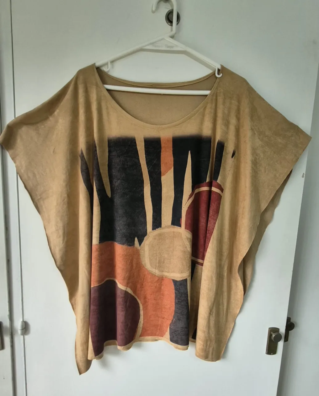Remera de diseño amplio y suelto, con estampa abstracta en tonos tierra y negro. Ideal para un look relajado y con onda.