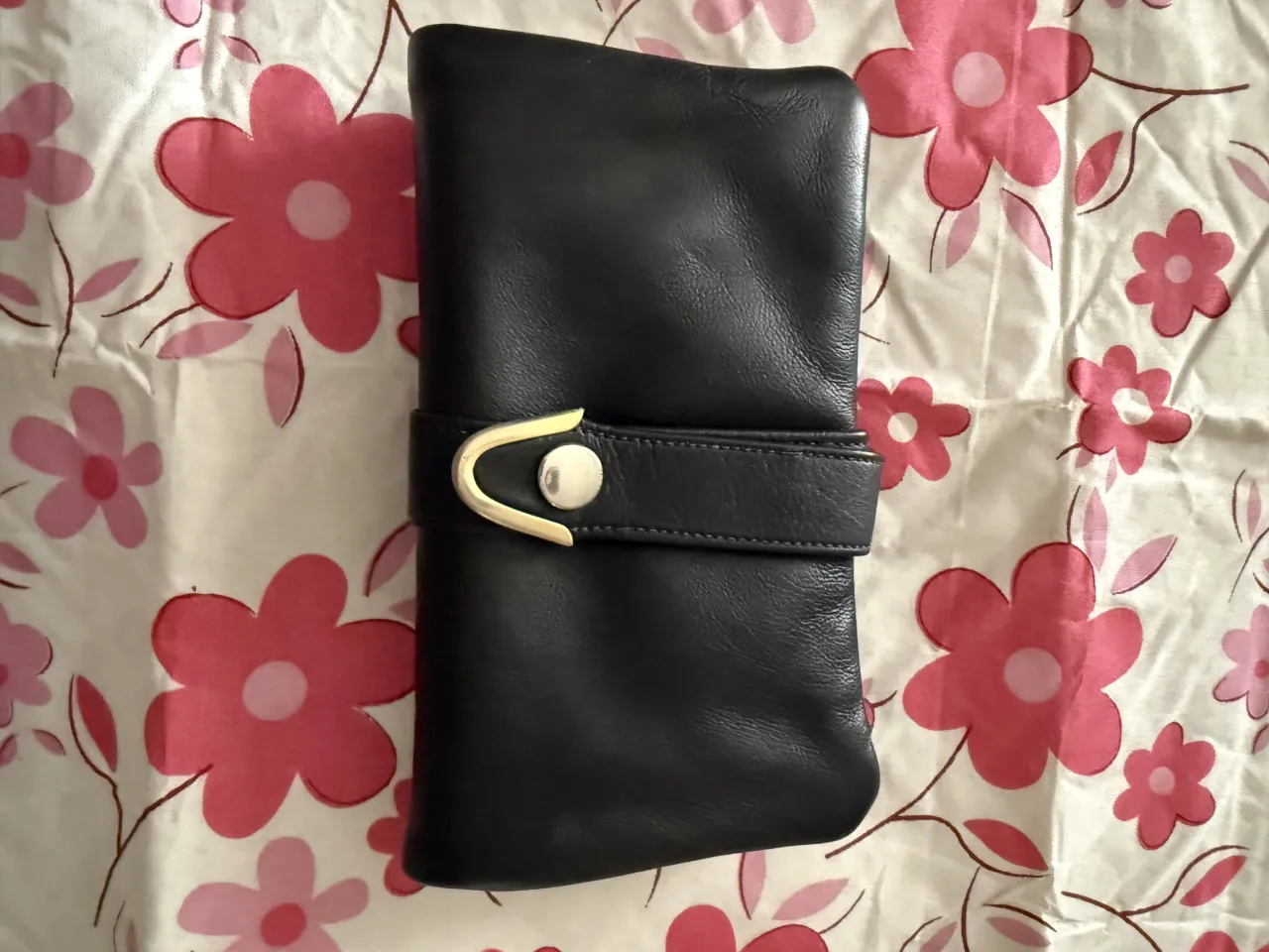 Cartera negra de cuero con cierre y detalle de hebilla dorada. Fabricada en Uruguay.