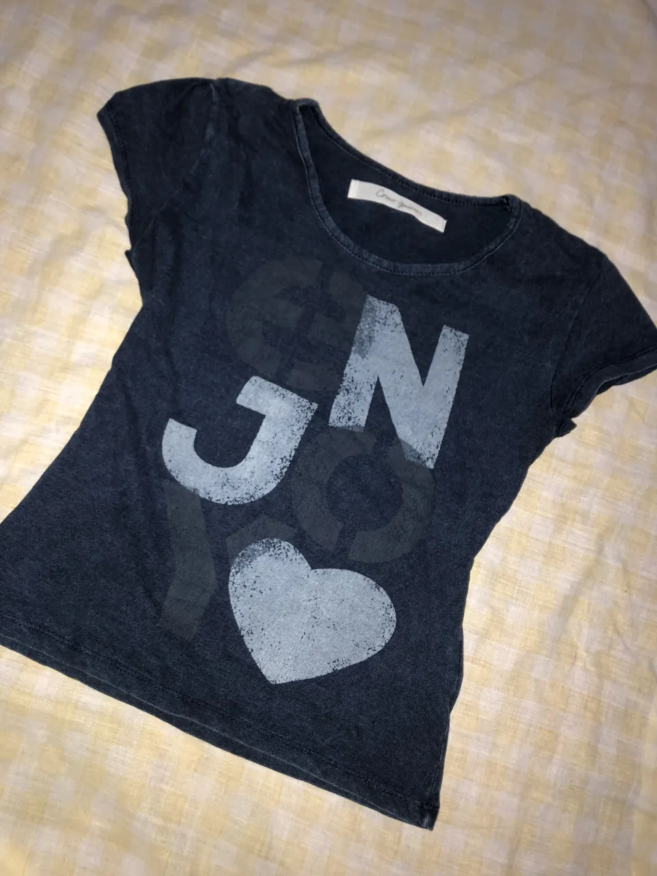 Remera de algodón color azul marino con estampa de letras y corazón en gris. Cuello redondo y mangas cortas.