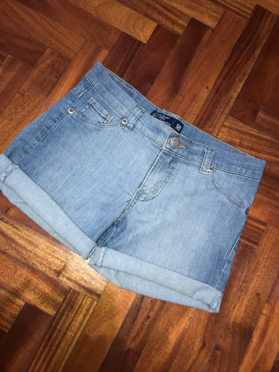 Shorts de jean tiro medio/bajo, con dobladillo regulable en los bordes inferiores. Posee bolsillos delanteros y traseros.