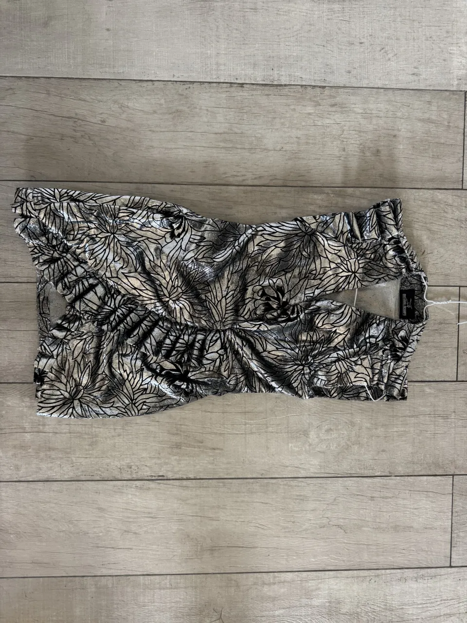 Vestido de diseñador, estampado con detalles plateados y negros. Posee fruncido en la cintura y escote con forma de corazón.