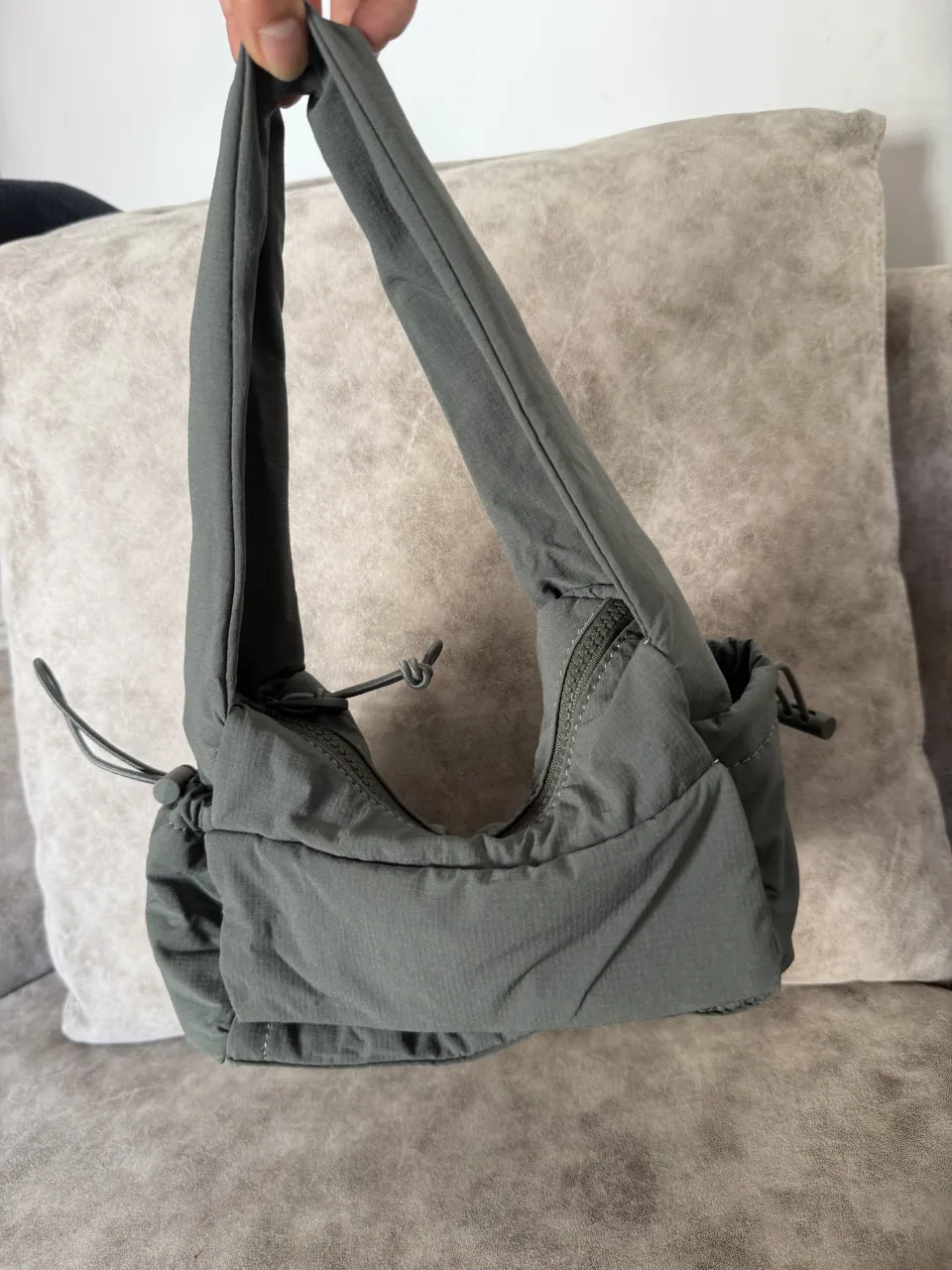 Bolsito de hombro tipo parachute gris verdoso, con cierre y detalles de fruncido. 