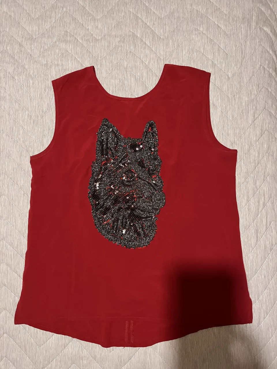Musculosa roja con aplique de lentejuelas y canutillos en forma de cabeza de perro en el frente.