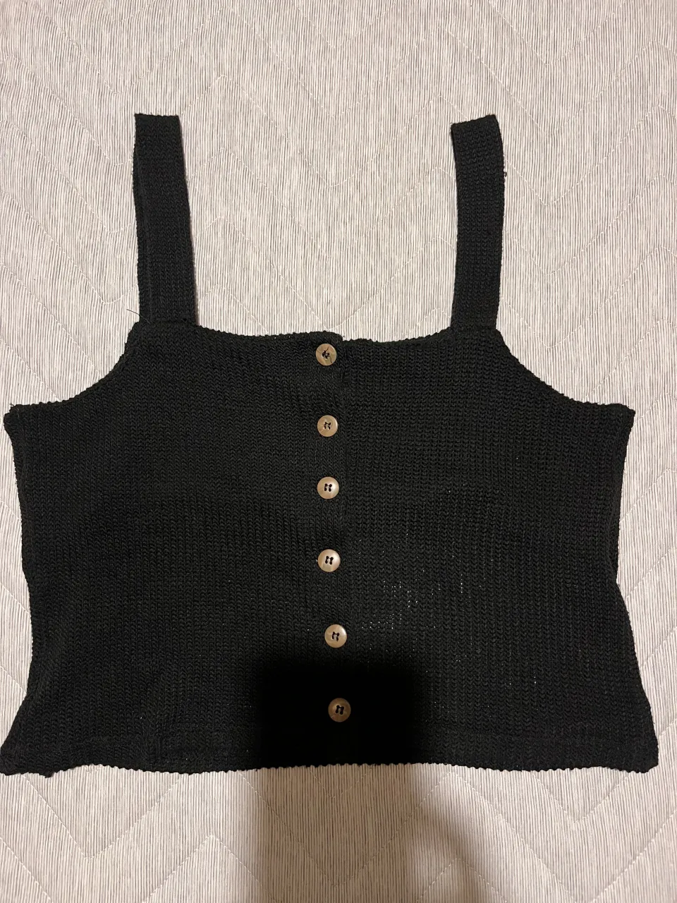 Top negro tejido con breteles anchos y botones al frente.
