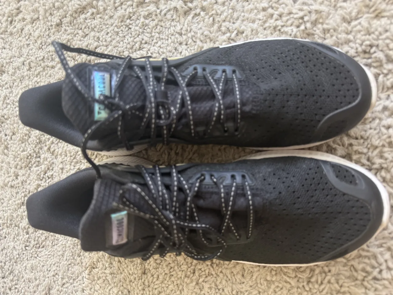 Zapatillas  Adidas deportivas negras con cordones blancos y detalles en blanco en la suela. Tienen tres tiras blancas características de la marca en el lateral.