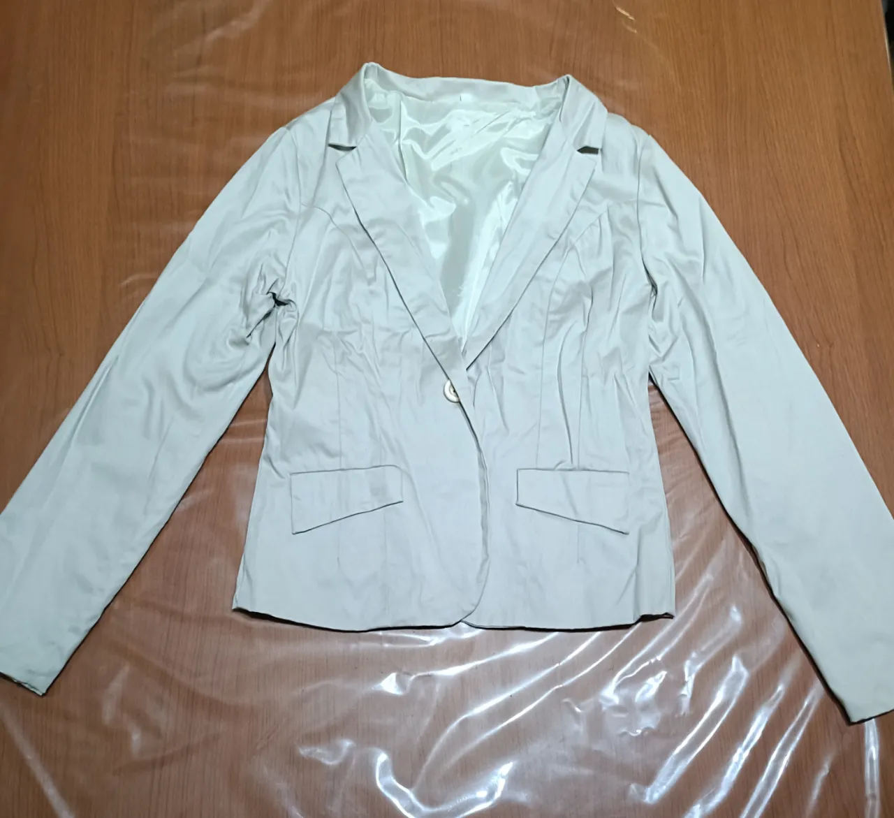 Blazer color crudo de vestir con un botón al frente al tono y dos bolsillos con solapa. Posee forro interior y la tela elastiza un poco.