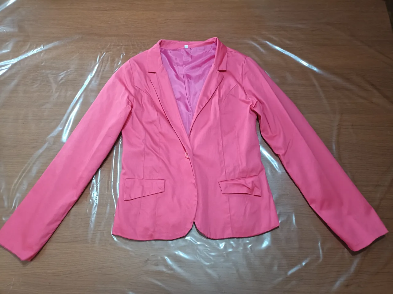 Blazer color fuxia de vestir con un solo botón al tono y dos bolsillos con solapa. Posee forro interior y la tela elastiza un poco.
El color fucsia es más oscuro de lo que sale en las fotos, en la última se nota un poco más el color real.