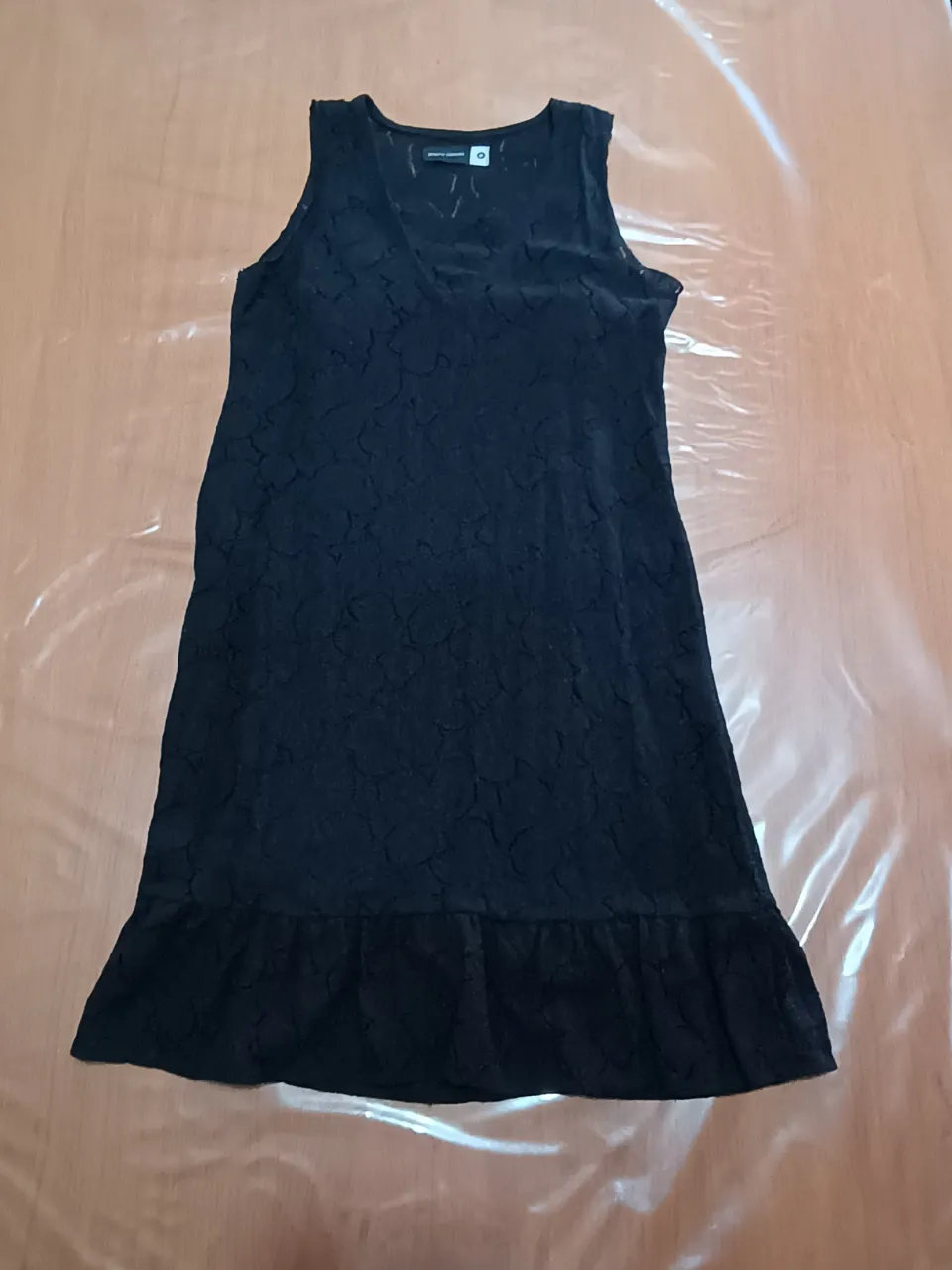 Vestido negro de encaje con volado en la falda. Tiene cuello en V y es sin mangas.
Posee unido un vestido negro de modal debajo para que no transparente. 