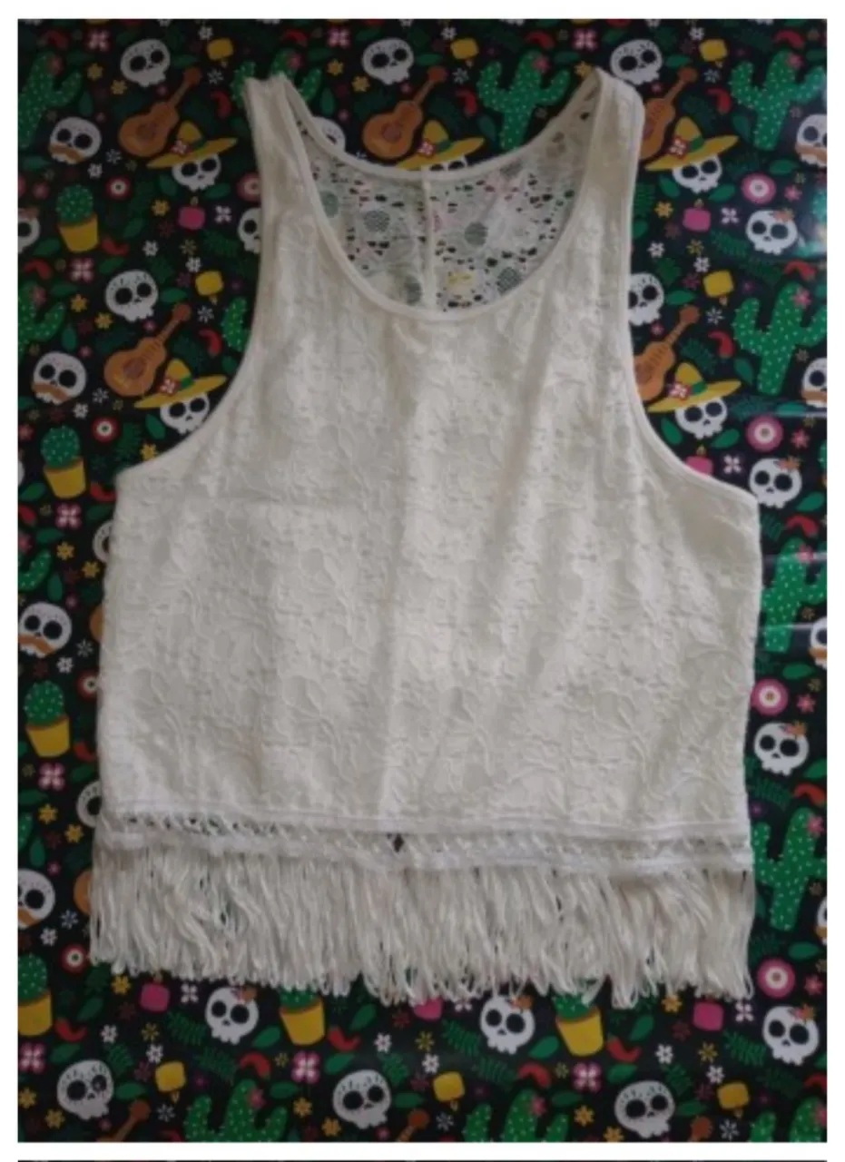 Musculosa elastizada blanca de encaje con flecos en la parte inferior. Pequeña bertura en la parte inferior de la espalda.