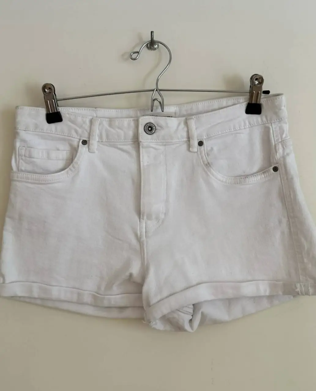 Short de jean blanco, tiro medio, con bolsillos delanteros y traseros. Ideal para un look casual y fresco.