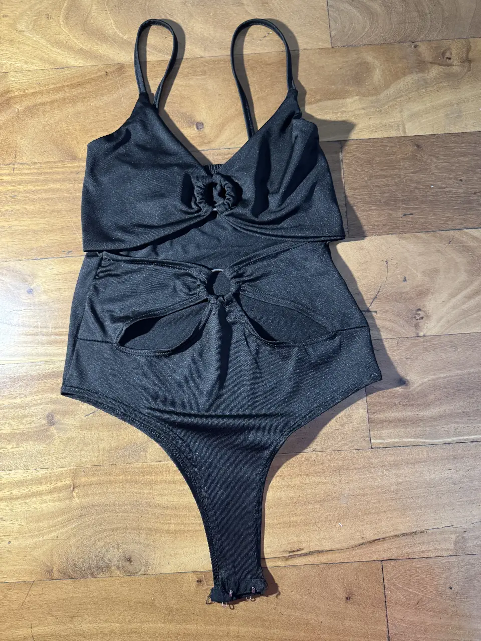 Body negro con diseño de moño en la parte delantera y corte en la zona de la cintura. Ideal para un look de fiesta o salida.