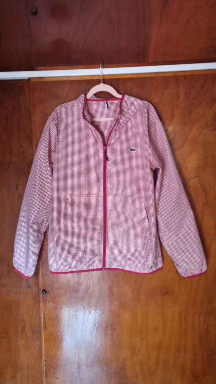 Campera a cuadros roja y blanca con cierre y capucha. Logo de cocodrilo bordado en el frente.