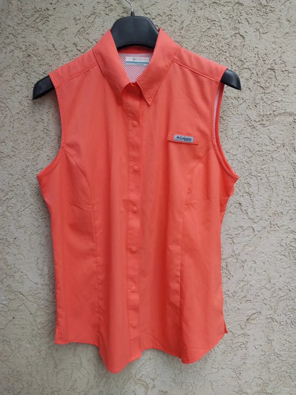 Remera sin mangas,treking columbia original, color naranja coral, con cuello camisero y botones al frente. Posee un pequeño logo de la marca en el bolsillo superior izquierdo. nueva a estrenar importada, calidad superior como toda prenda de esta marca