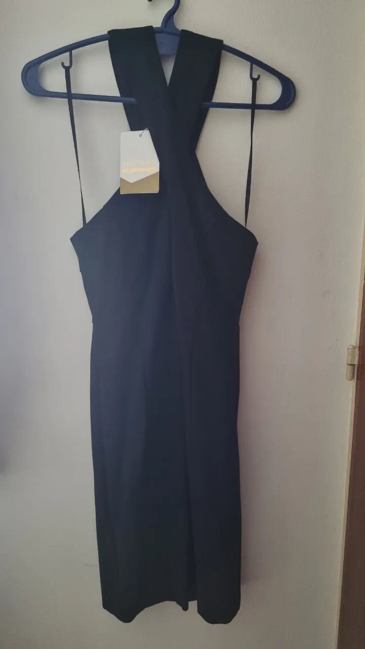 Vestido negro con escote cruzado y tiras finas. Posee cierre en la espalda y abertura en la zona del busto. Talle 40 (S/M)