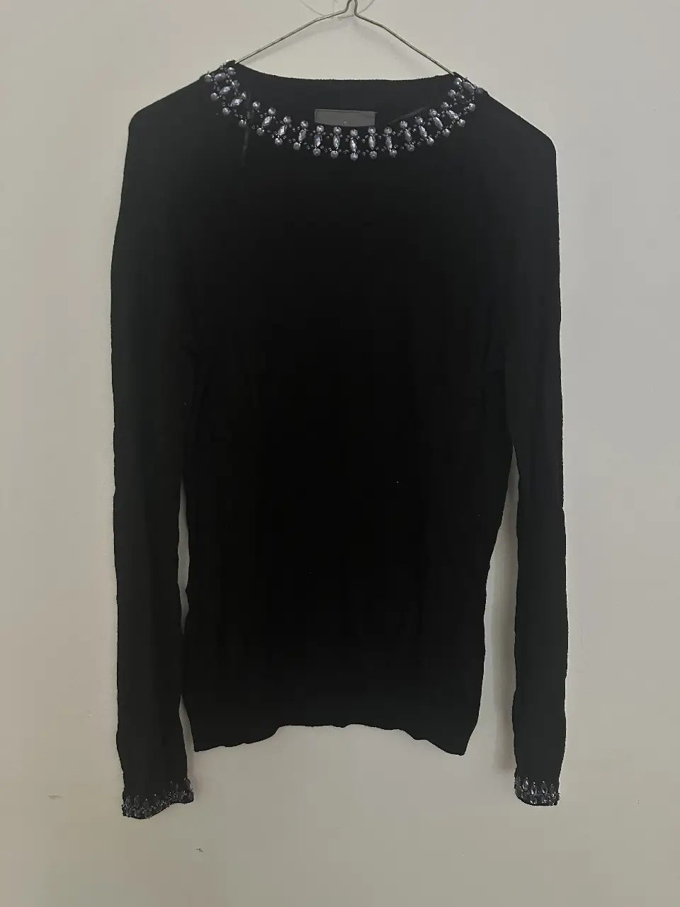 Sweater negro de manga larga con detalles de piedras en el cuello y puños. Talle M, ideal para un look elegante y sofisticado.