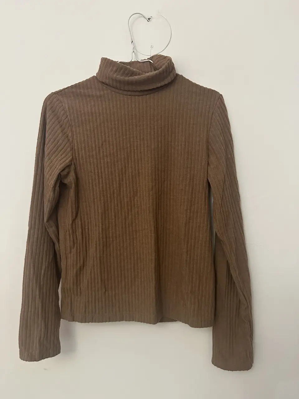 Remera manga larga de cuello alto, color marrón, ideal para el invierno. Confeccionada en tejido de punto acanalado, ofrece un ajuste ceñido y un estilo moderno y versátil.