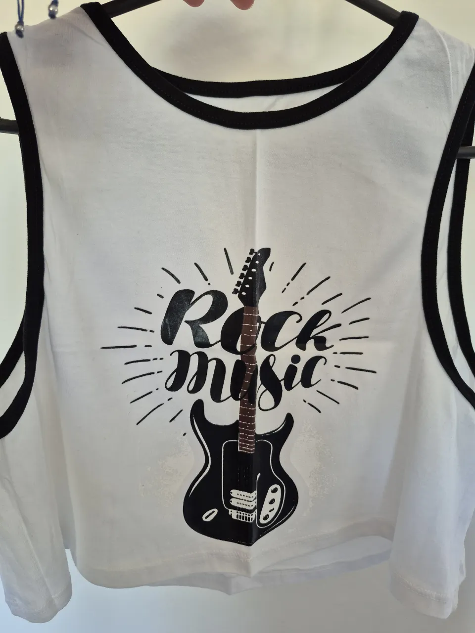 Musculosa blanca con estampa de guitarra eléctrica y la frase "Rock music". Tiene ribetes negros en cuello y mangas.