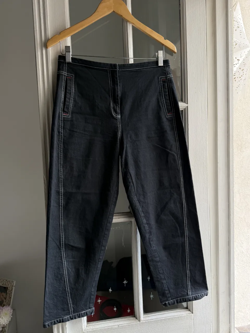 Pantalón negro con costuras blancas y detalles en rojo. Tiene bolsillos frontales y traseros.