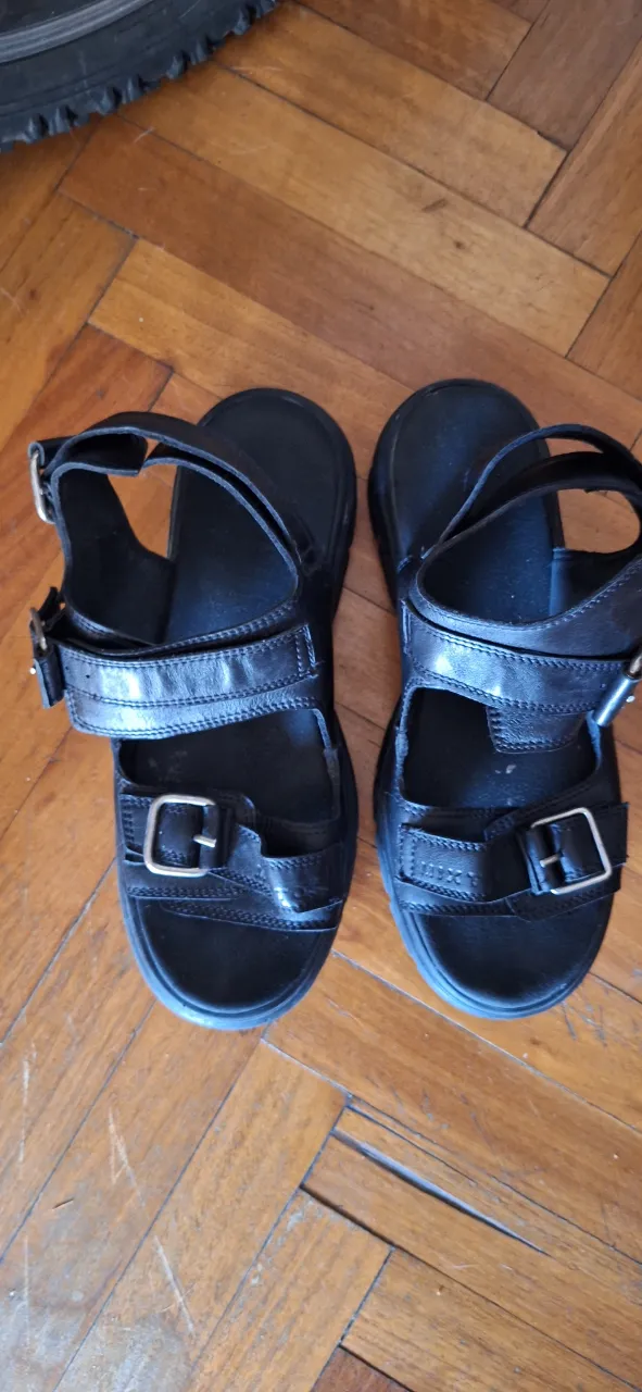 Sandalias negras con tiras y hebillas plateadas. Suela gruesa.
Muy buena calidad, algo pesadas.