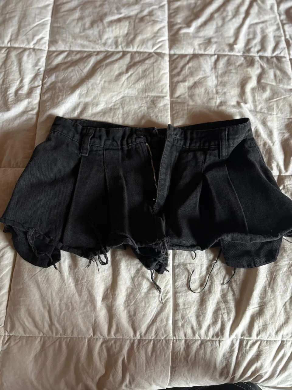 Shorts de jean negros con roturas y detalles deshilachados en el ruedo. Poseen un diseño plisado como pollera tableada en la parte delantera y cierre. TALLE 38/40 (soy 36 y me queda bien, tiro demasiado bajo)