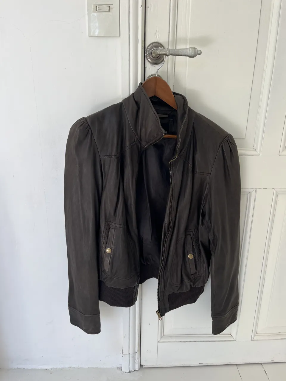 Campera de cuero marrón con cuello mao, cierre al frente y bolsillos con solapa y botón. Puños y cintura elastizados.