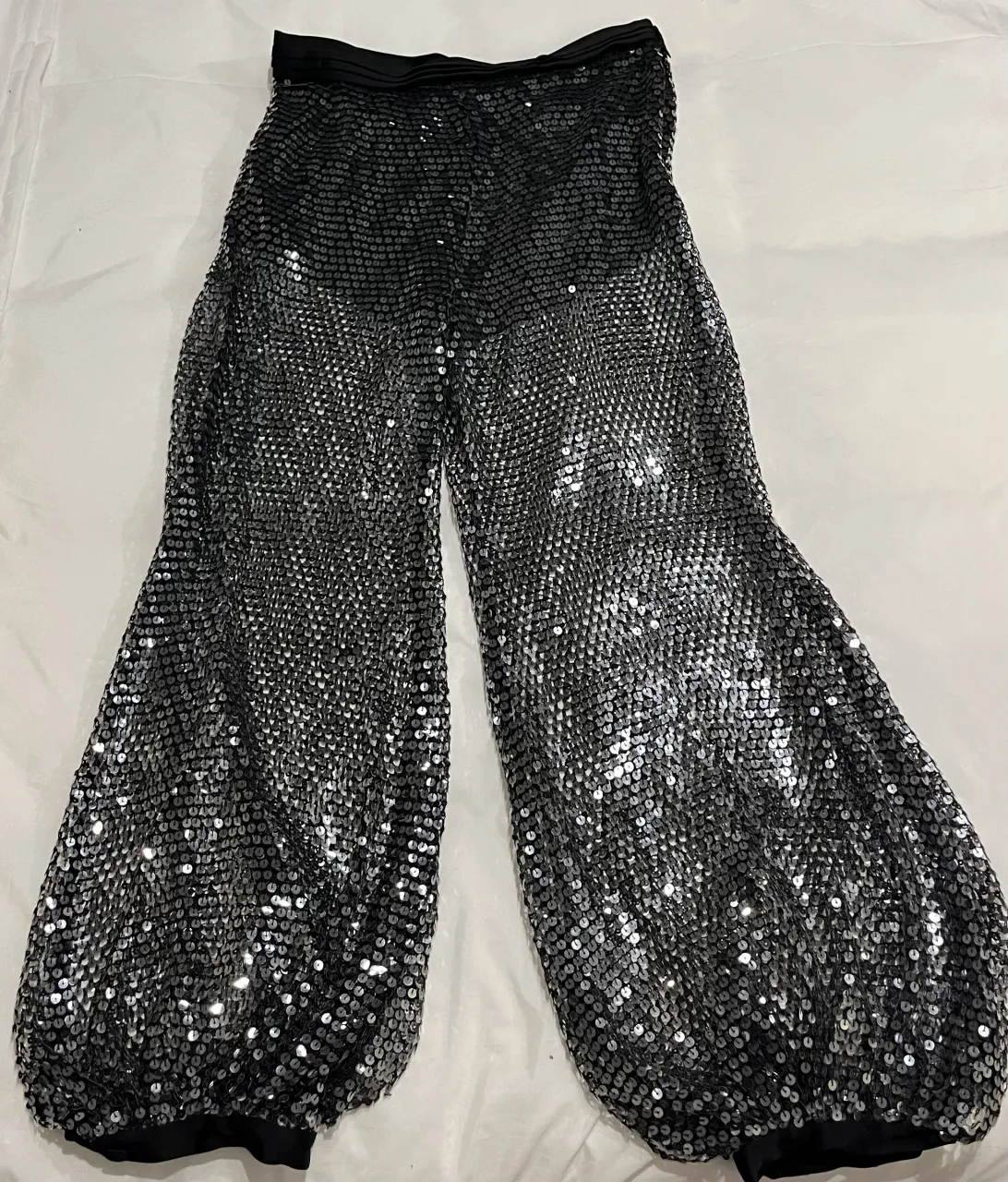 Pantalones negros con lentejuelas plateadas. Cintura elastizada.