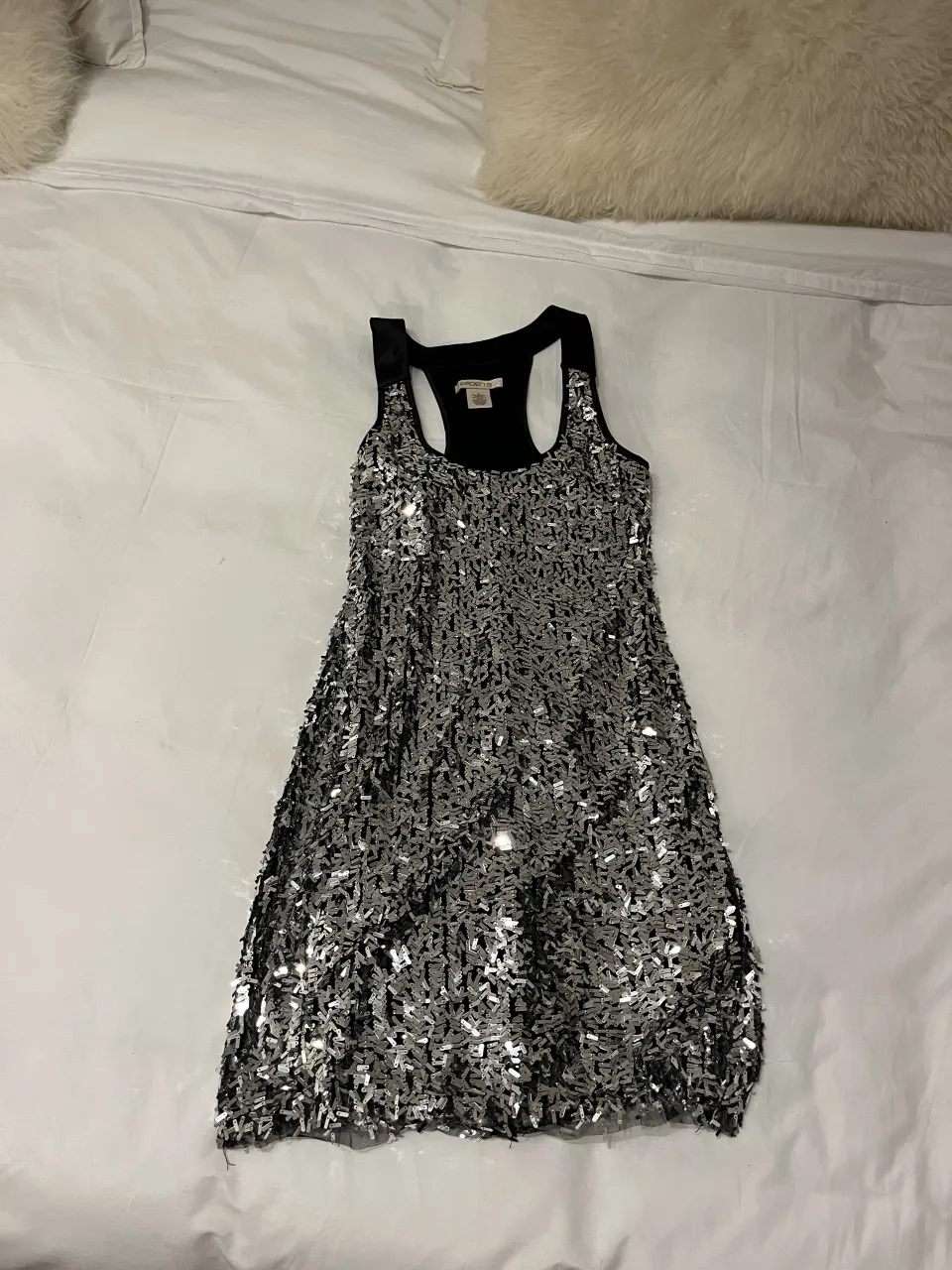 Vestido corto plateado con lentejuelas y escote redondo.