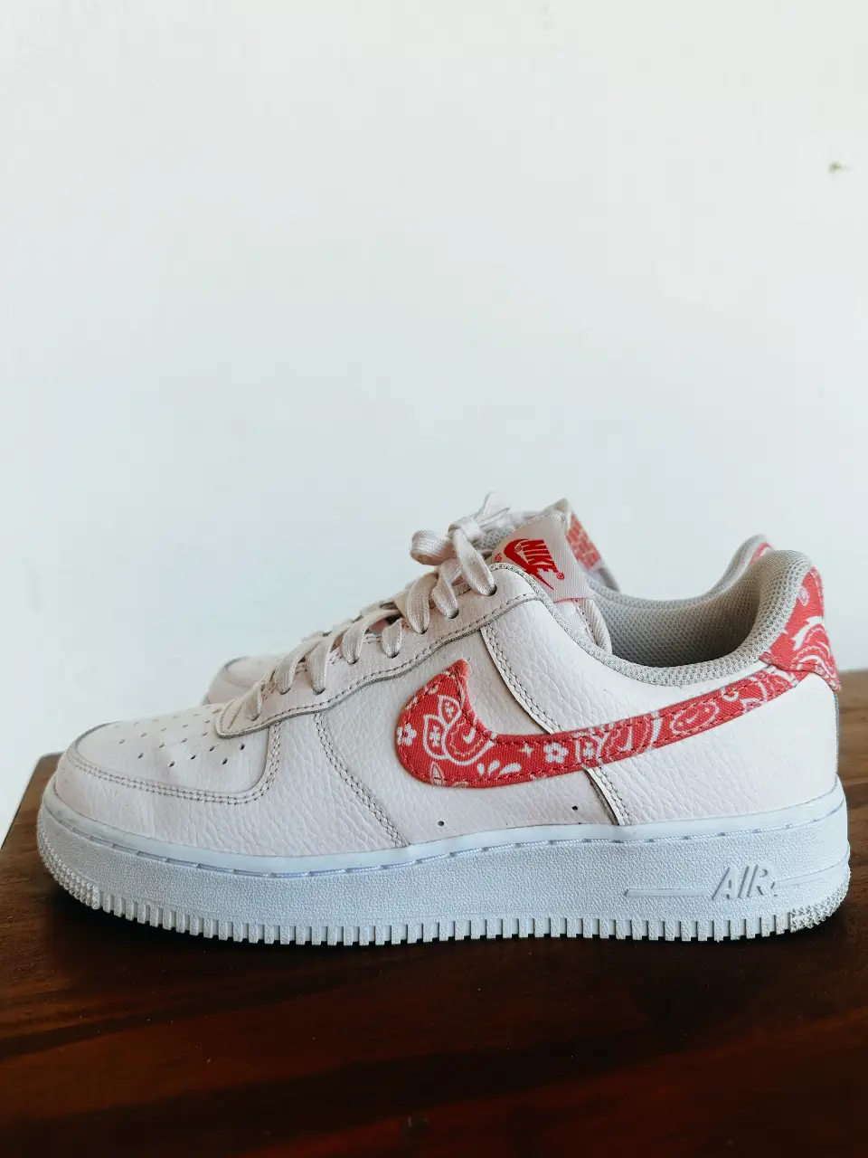 Zapatillas Nike Air Force 1 con diseño de bandana en el logo y talón. Color rosa claro con detalles en rojo.