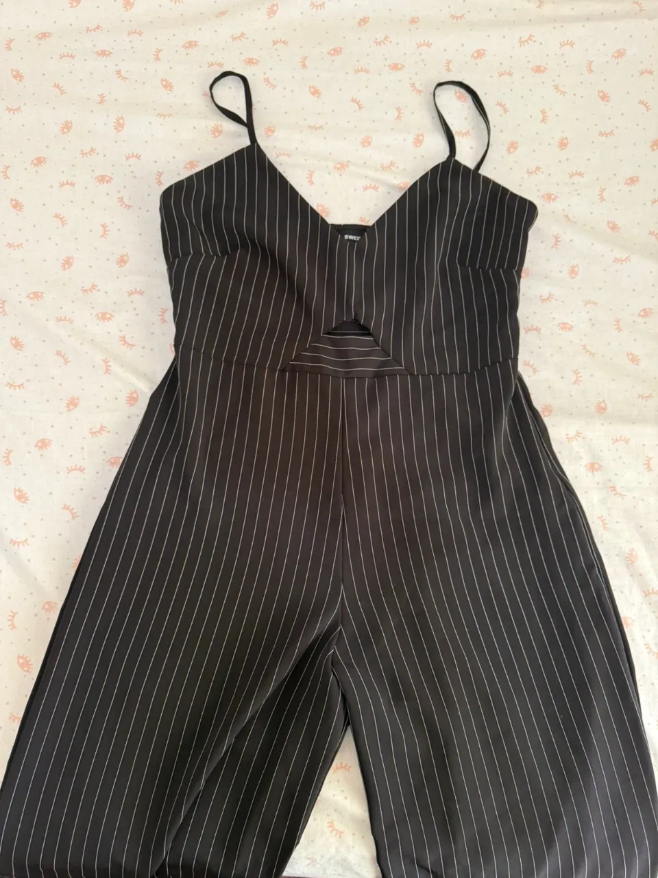 Mono negro con finas rayas blancas verticales. Posee breteles finos y un recorte triangular en la zona del busto.