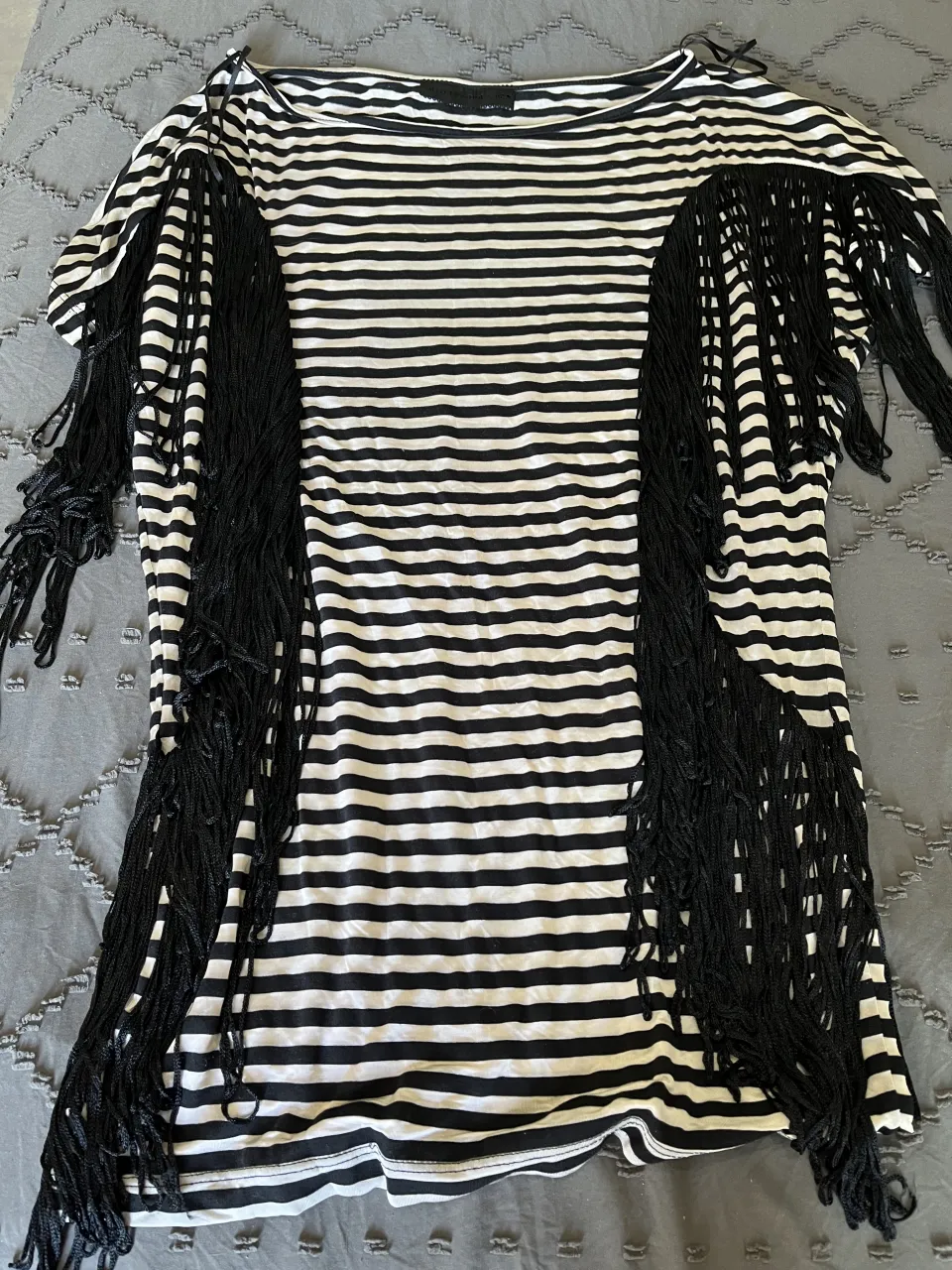 vestido  a rayas blancas y negras con flecos largos en los hombros. Un diseño audaz y moderno para destacar tu estilo.