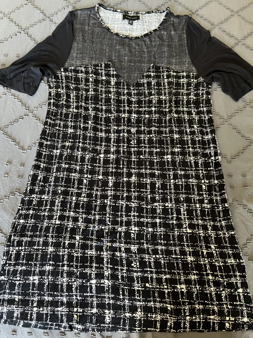 Vestido corto de tela tipo tweed con mangas de red y cuello redondo. Diseño a cuadros en blanco y negro, ideal para un look elegante y moderno. talle 40