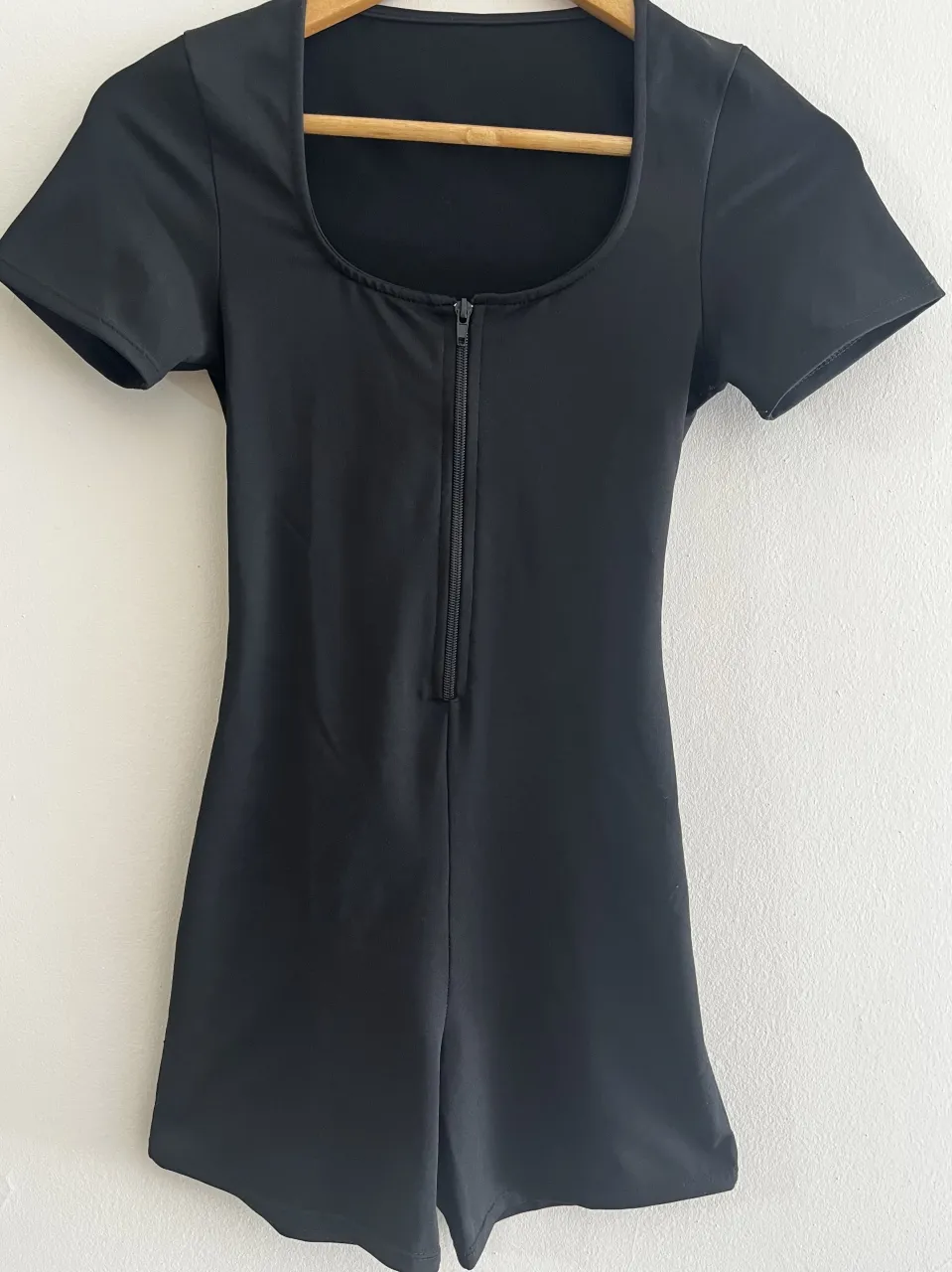 Catsuit de manga corta con escote cuadrado y cierre delantero. Posee una abertura circular en la espalda.