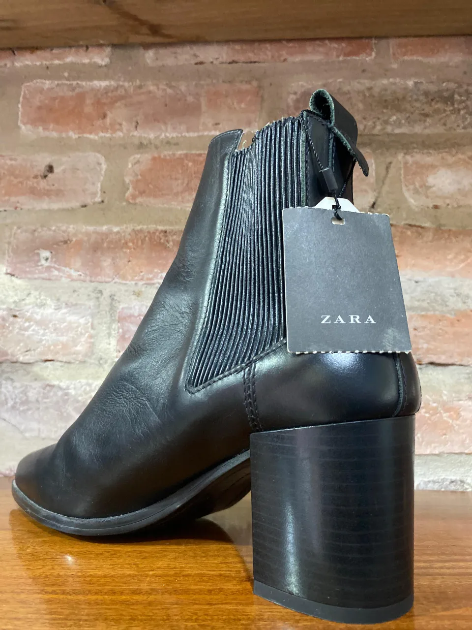 Botas de cuero negras con elástico a los costados y taco grueso. Las botas grises son de gamuza con detalles de perforaciones y flecos.