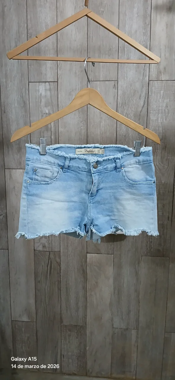 Shorts de jean tiro alto con roturas y flecos en cintura y  ruedo. Lavado celeste claro.