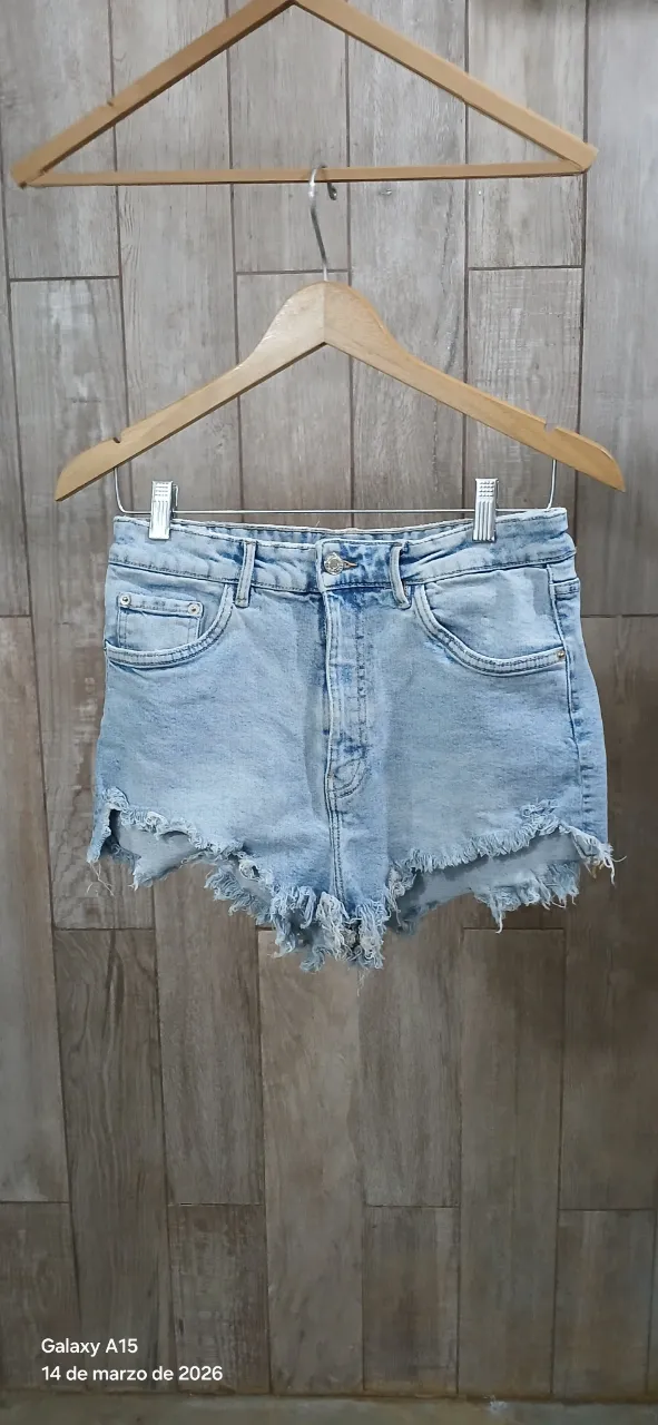 Shorts de jean tiro alto con roturas y detalles deshilachados en el borde inferior. Lavado celeste.