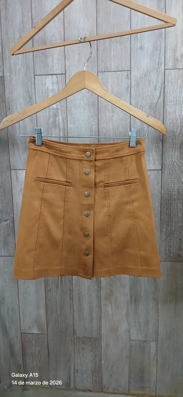 Pollera marrón de gamuza sintética elastizada, con broches oro viejo al frente y bolsillos simulados.