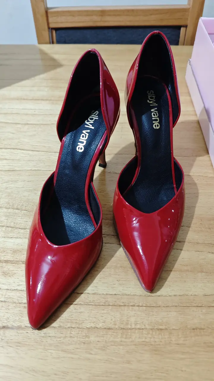 Elegantes zapatos de taco alto rojos de charol, con diseño de corte asimétrico y punta fina. Ideales para eventos formales y fiestas. Un solo uso, impecable sin ningún detalle.