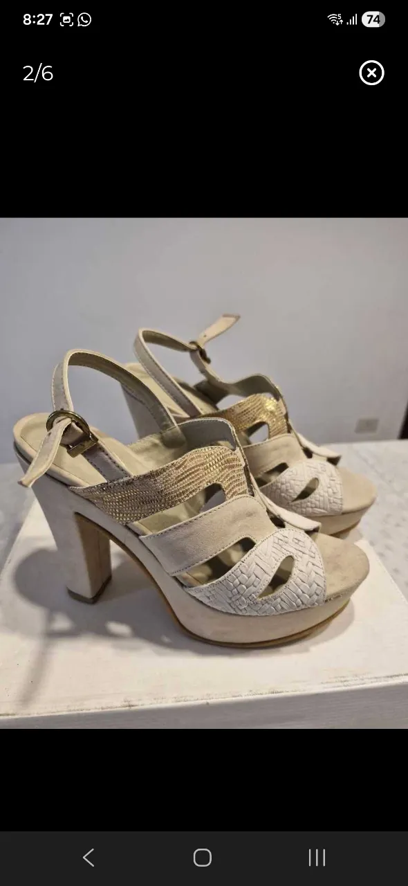 Sandalias de taco alto color beige con detalles dorados y texturas tejidas en la capellada. Tienen tiras ajustables con hebilla.