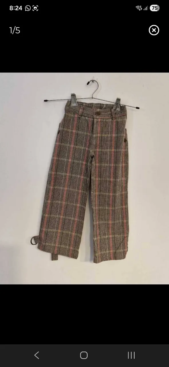 Pantalón de tela a cuadros escoceses en tonos marrones, rosas y blancos. Posee dos bolsillos delanteros y dos traseros. El bajo del pantalón tiene un detalle de lazo.