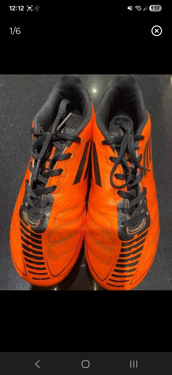 Botines de fútbol Adidas Naranja y Negro. Ideales para jugar en césped. ¡Listos para la cancha!