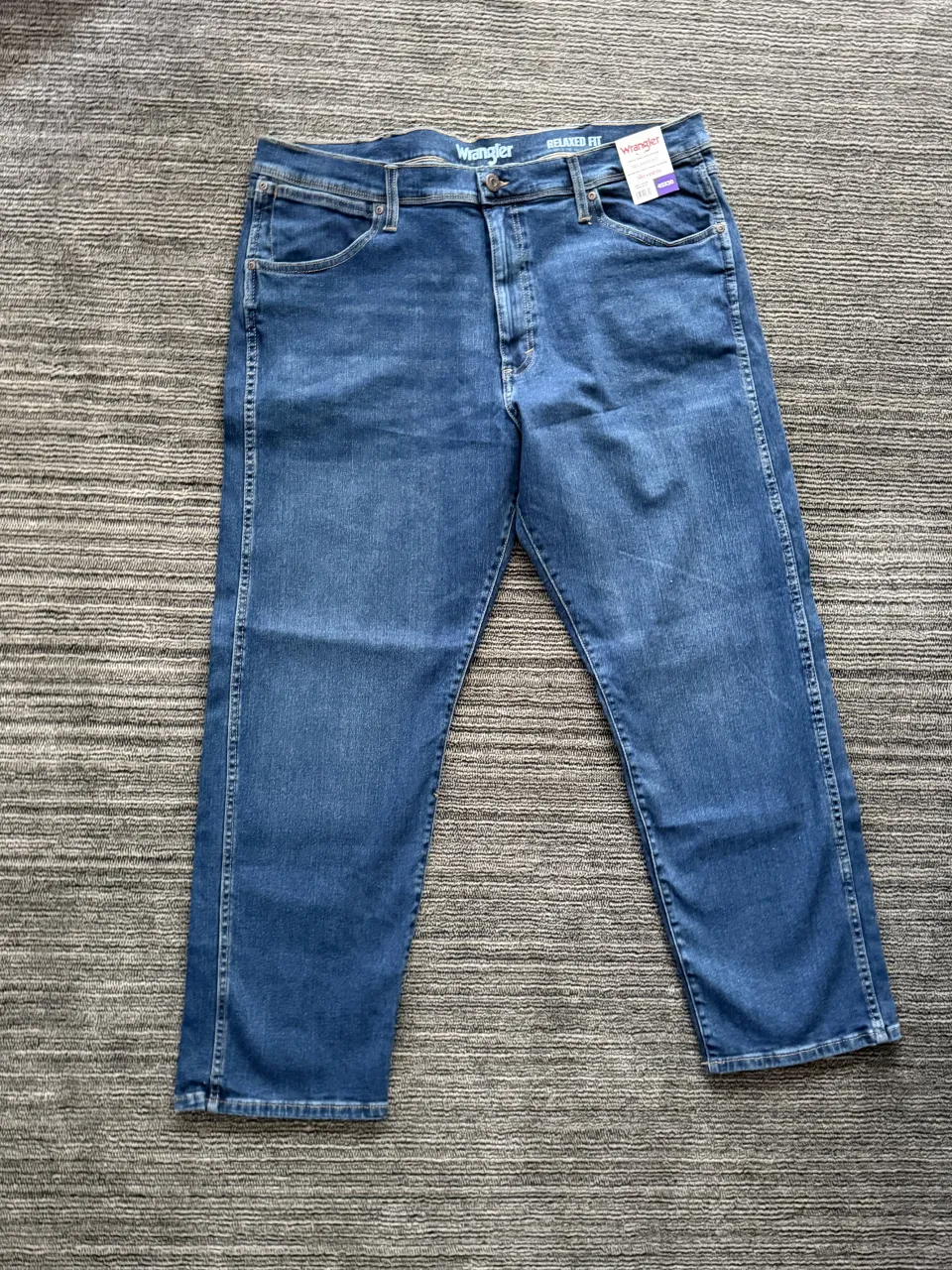 Jeans de corte relajado de mezclilla azul oscuro. Cuentan con cinco bolsillos y cierre de botón y cremallera.