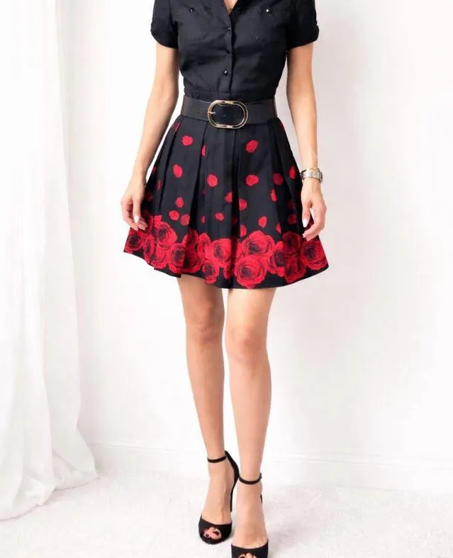 Vestido negro con estampado de rosas rojas en la falda. Posee cuello de camisa, mangas cortas.
