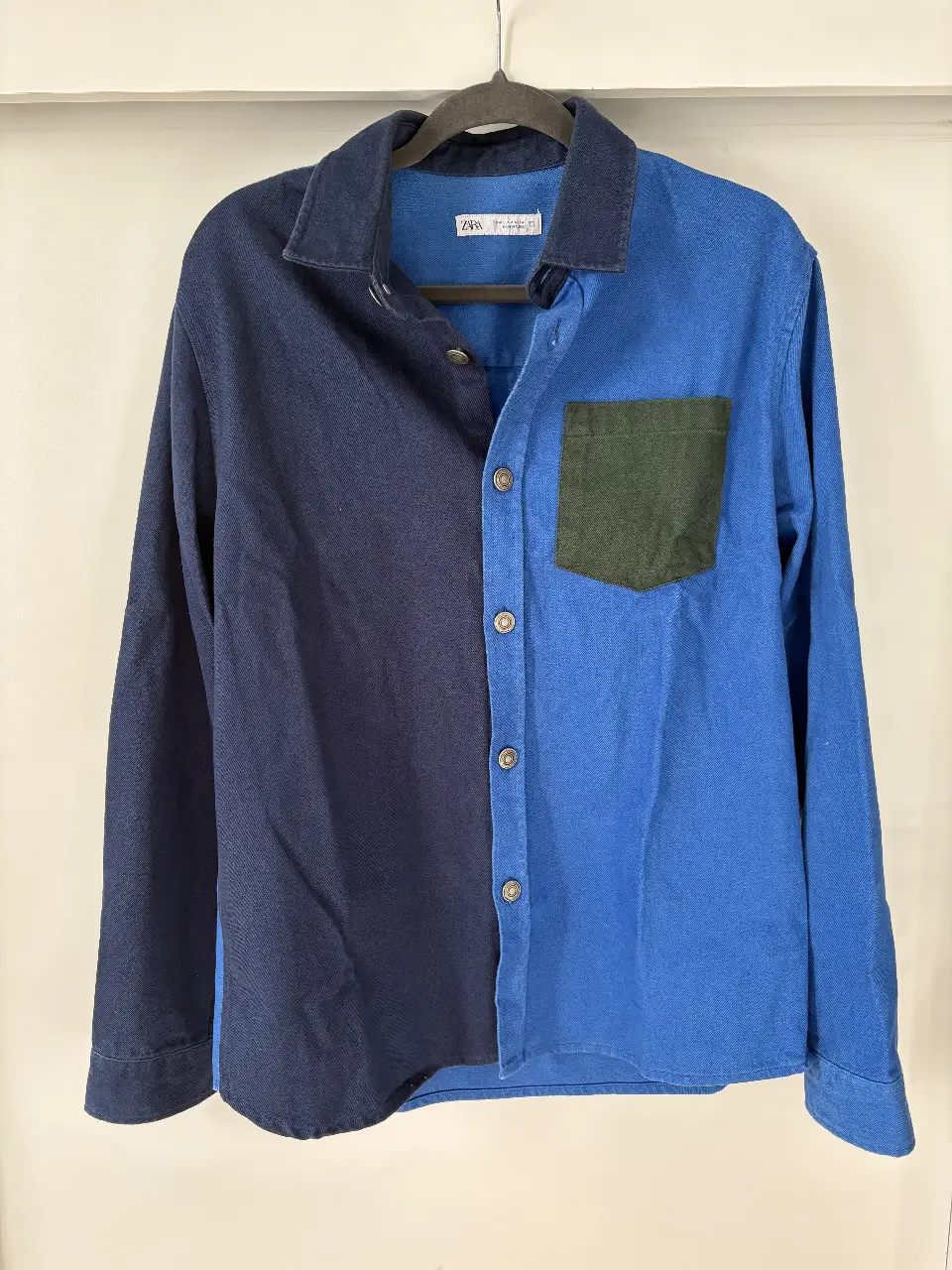 Camisa de hombre Zara, manga larga, con diseño bicolor en azul y bolsillo verde. Ideal para un look casual y moderno.