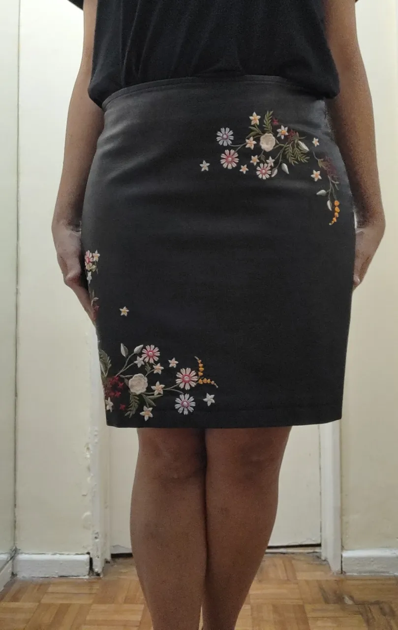 Pollera corta de cuero sintético negra con bordados de flores en el frente. Tiene cierre en la parte del costado. Tiene poco uso, y el detalle en la parte del cierre muestro en las dos últimas fotos. Es mínimo, porque tanto el frente como la parte trasera están impecable. Por dentro completamente forrada.

Detalle de medidas
Talle 44/M
Largo total 45 cm 
Cintura 43 cm 
Cadera 52 cm