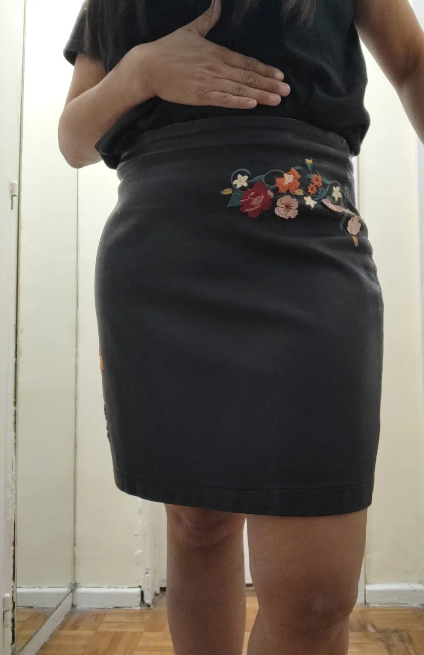 Pollera corta de cuero sintético negra con bordados de flores en el frente. Tiene cierre en la parte del costado. Está impecable, un solo uso! Por dentro completamente forrada.

Detalle de medidas
Talle 44/M
Largo total 45 cm 
Cintura 42 cm 
Cadera 52 cm 